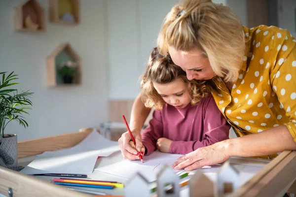 Милая маленькая девочка с мамой в помещении дома, рисует картины . — стоковое фото