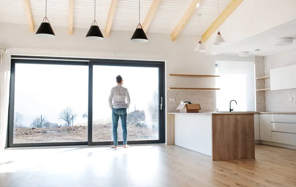 Vue arrière de l'homme debout dans une maison non meublée, déménageant dans un nouveau concept de maison . — Photo