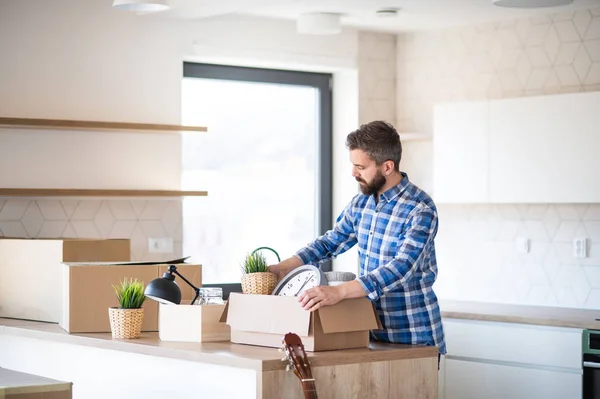 Hombre maduro con cajas moviéndose en casa nueva sin amueblar, desempacando . — Foto de Stock