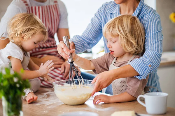 Középső részén fiatal család két kisgyerekkel beltéri konyhában, főzés. — Stock Fotó