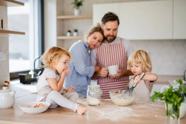 Молода сім'я з двома маленькими дітьми в приміщенні на кухні, приготування їжі . — стокове фото