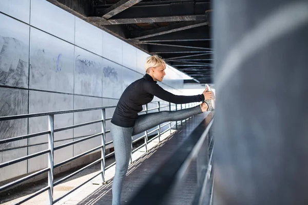 Porträt einer jungen Sportlerin, die im Freien Sport treibt, sich dehnt. — Stockfoto