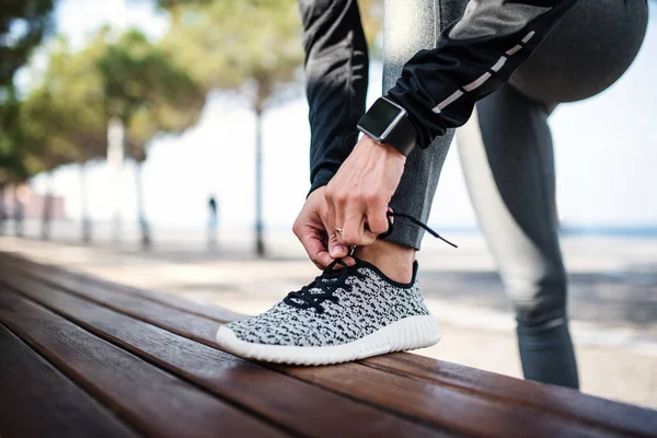 Una joven deportista con smartwatch al aire libre en la ciudad, atando cordones . —  Fotos de Stock