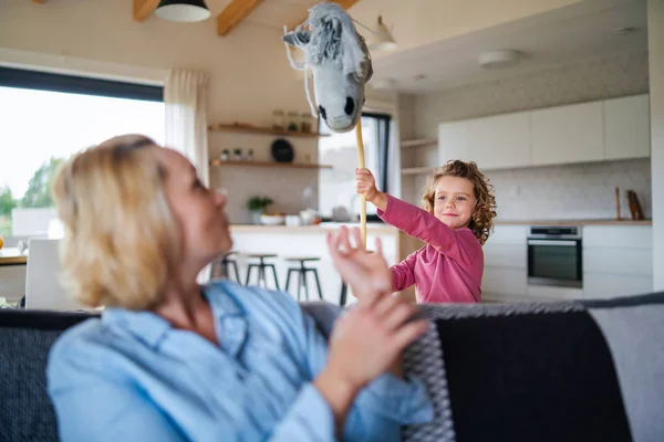 En söt liten flicka med mamma inomhus, leker. — Stockfoto