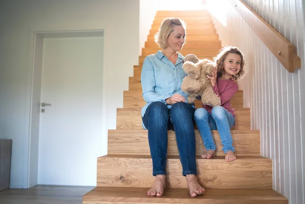 Симпатична маленька дівчинка з мамою вдома, сидить на сходах . — стокове фото