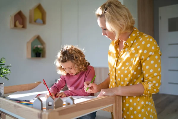 Una piccola ragazza carina con la madre al chiuso a casa, disegni . — Foto Stock