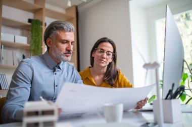 Ofisteki masada oturan mimarlar, planlara bakıyorlar..