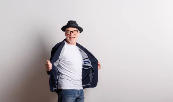 Retrato de un hombre mayor con sombrero, gafas y chaqueta en un estudio . —  Fotos de Stock