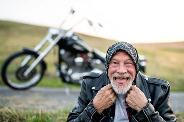 Wesoły starszy mężczyzna podróżnik z motocyklem na wsi, zabawy. — Zdjęcie stockowe