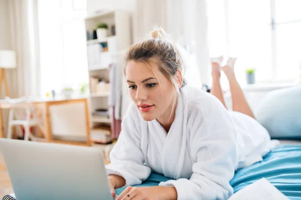 Νεαρή γυναίκα με φορητό υπολογιστή στο κρεβάτι στο σπίτι το πρωί. — Φωτογραφία Αρχείου