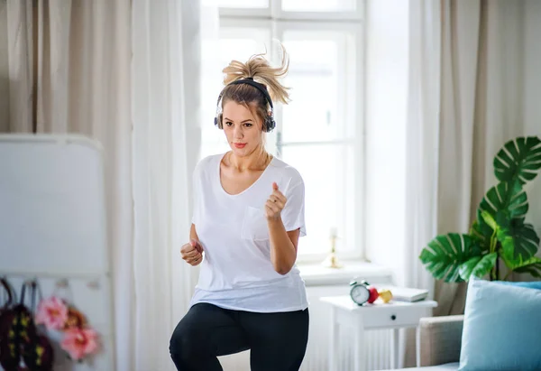 Junge Frau mit Kopfhörern übt zu Hause im Schlafzimmer. — Stockfoto