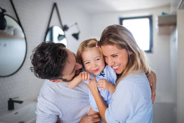 Young family with small daughter indoors in bathroom, hugging. — Stock Photo, Image