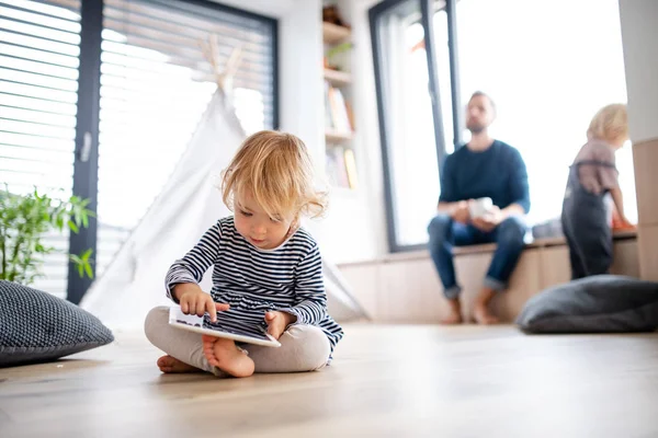 Linda niña pequeña en el interior del dormitorio jugando con la tableta . — Foto de Stock