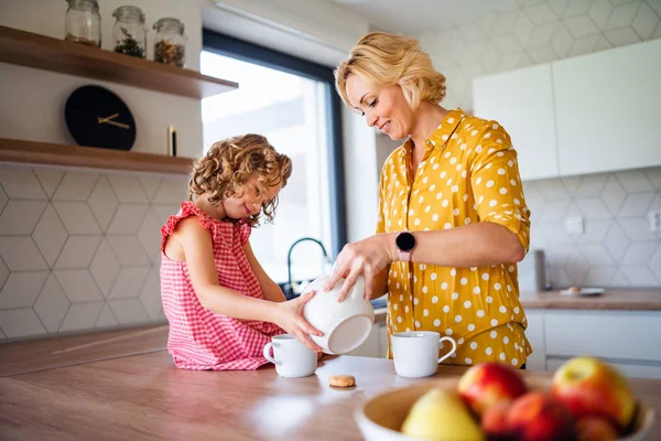 Een schattig klein meisje met moeder binnen in de keuken thuis. — Stockfoto