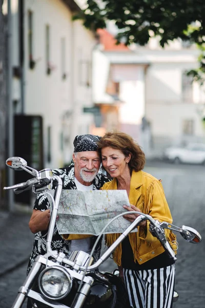 Ein fröhliches älteres Ehepaar, das mit dem Motorrad in der Stadt unterwegs ist, mit Karte. — Stockfoto