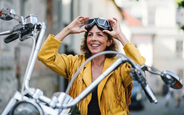 城市里骑摩托车的快乐的老年妇女. — 图库照片