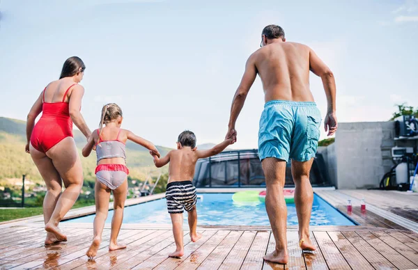 Vue arrière de la famille avec deux jeunes enfants près de la piscine extérieure . — Photo