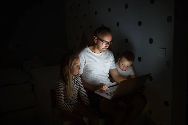 Padre con los niños sentados en el interior del dormitorio, utilizando el ordenador portátil . — Foto de Stock