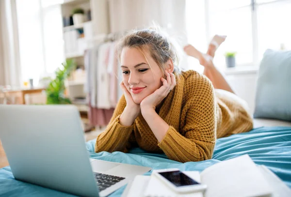 Ung kvinna med laptop liggande på sängen inomhus, avkopplande. — Stockfoto