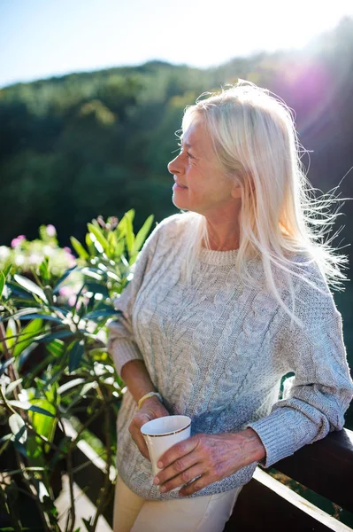 Donna anziana con caffè in piedi all'aperto sulla terrazza, a riposo . — Foto Stock