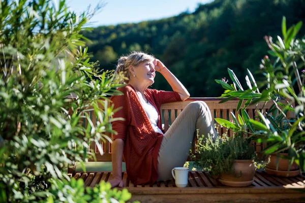 Mujer mayor con café sentado al aire libre en la terraza, descansando . — Foto de Stock