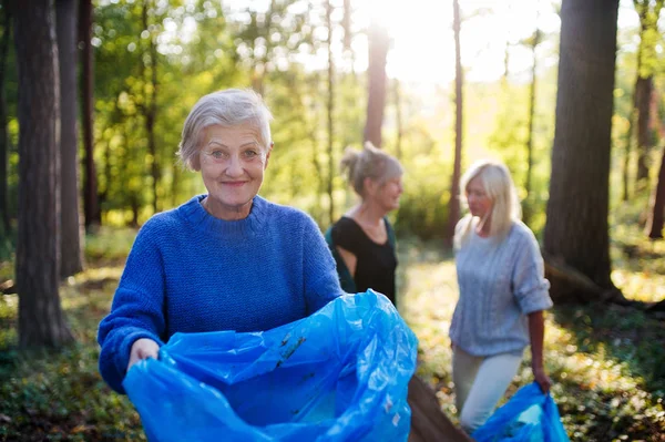 Starsze kobiety przyjaciele zbieranie śmieci na zewnątrz w lesie a plogging koncepcja. — Zdjęcie stockowe