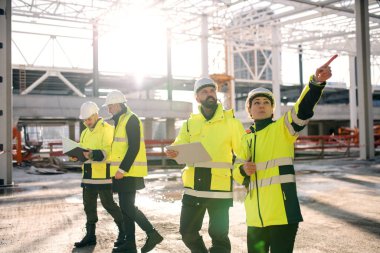 Group of engineers standing outdoors on construction site, working.
