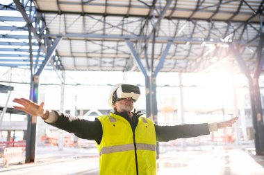 Man engineer using VR goggles on construction site.