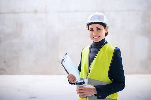 Egy női mérnök áll a betonfal mellett az építkezésen.. — Stock Fotó
