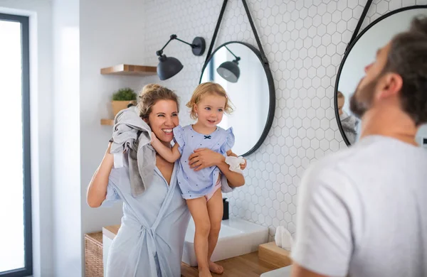 Jonge familie met kleine dochter binnen in de badkamer, praten. — Stockfoto