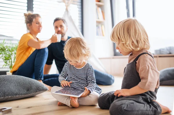 Familia joven con dos niños pequeños en el interior del dormitorio usando tableta . — Foto de Stock