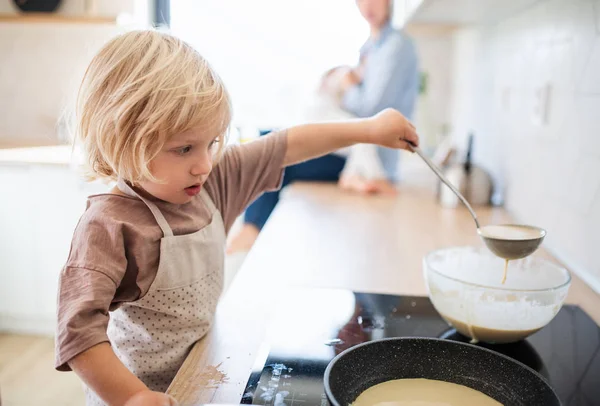 Egy kisfiú segít a konyhában palacsintát sütni.. — Stock Fotó