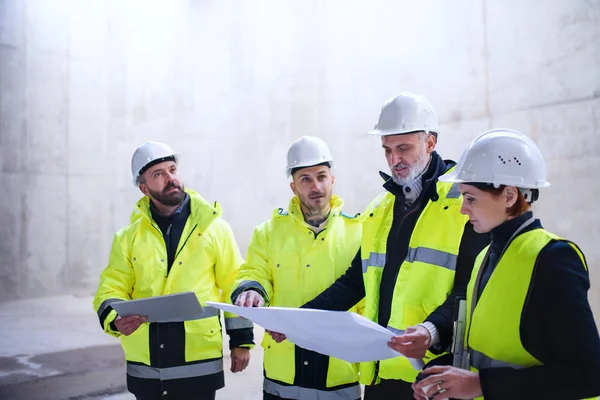 A group of engineers standing on construction site, holding blueprints. — 스톡 사진