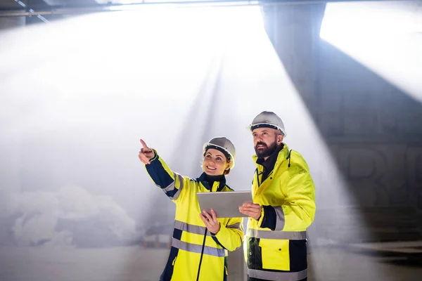 Engineers standing outdoors on construction site, holding tablet. — 스톡 사진