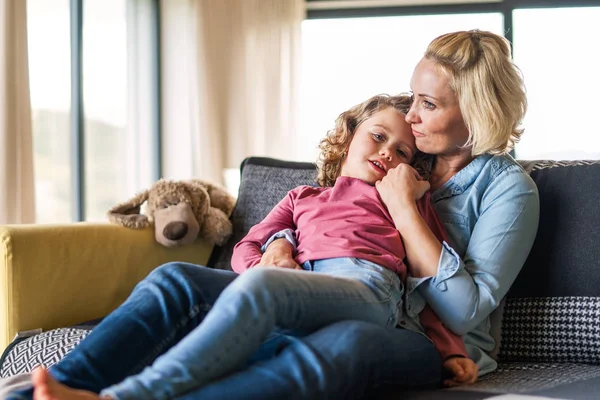 Söt liten flicka med mamma på soffan inomhus, vilar. — Stockfoto