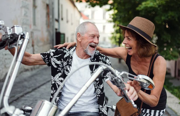Un cuplu vesel de bătrâni călători cu motocicletă în oraș . — Fotografie, imagine de stoc