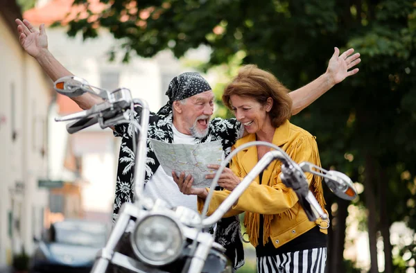 Ένα χαρούμενο ζευγάρι ηλικιωμένων ταξιδιωτών με μοτοσικλέτα στην πόλη, χρησιμοποιώντας το χάρτη. — Φωτογραφία Αρχείου