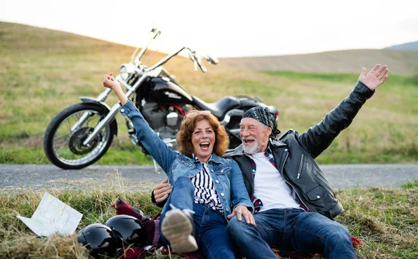 A cheerful senior couple travellers with motorbike in countryside. — Stock Photo, Image