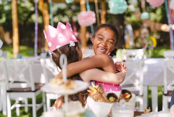 Små flickor kramas utomhus i trädgården på sommaren, födelsedagsfirande koncept. — Stockfoto