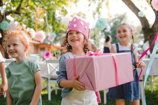Портрет маленькой девочки с друзьями и подарок на открытом воздухе в саду летом . — стоковое фото