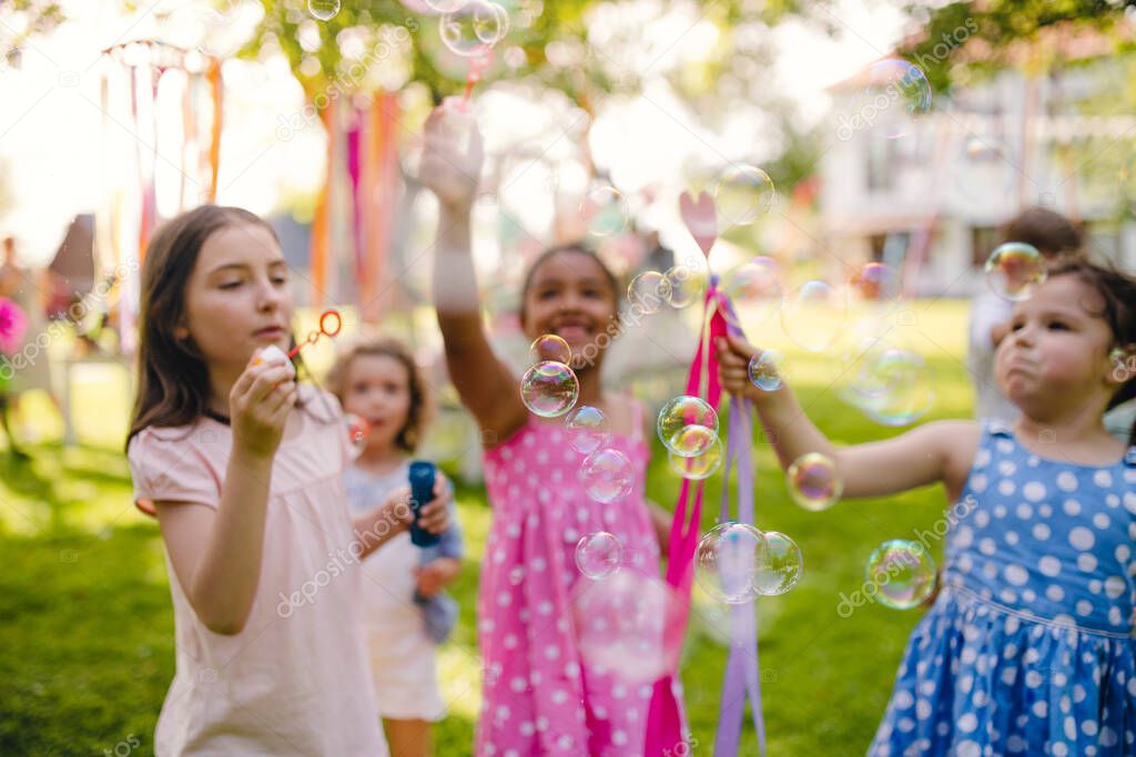 Small children standing outdoors in garden in summer, playing.