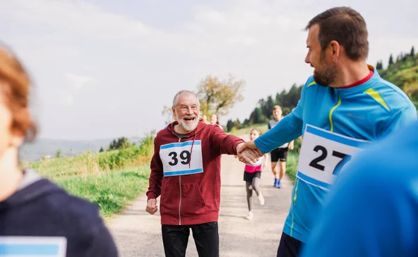 Gran grupo de personas de varias generaciones corriendo una competición de carreras en la naturaleza . — Foto de Stock