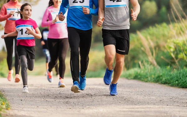 Sección media de un gran grupo de personas corriendo una competición de carreras en la naturaleza . — Foto de Stock