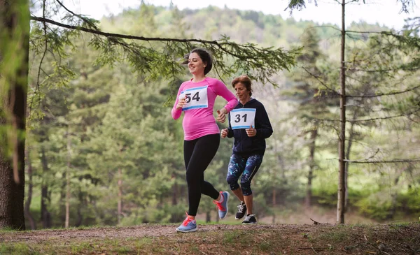 Mujer embarazada corriendo una competición de carreras en la naturaleza . — Foto de Stock