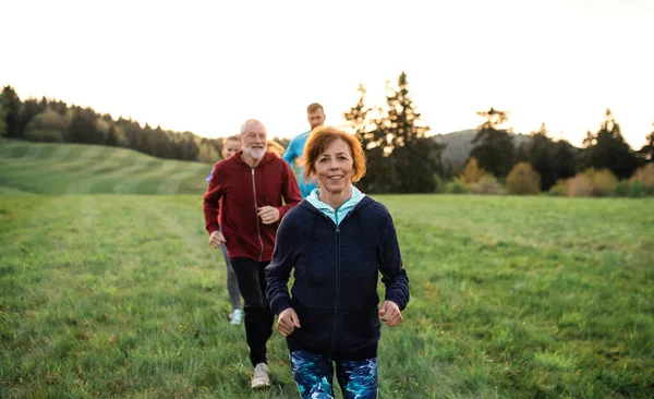 En stor grupp människor korsar land som springer i naturen. — Stockfoto