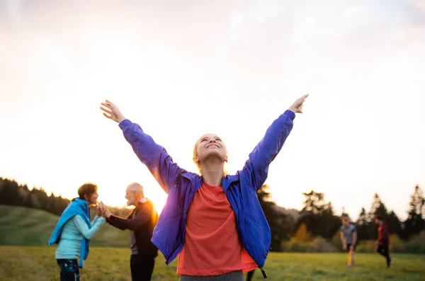 A portrait of young woman with large group of people doing exercise in nature. — Stock Photo, Image