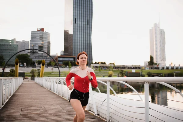 Junge Läuferin joggt mit Kopfhörern in der Stadt. — Stockfoto