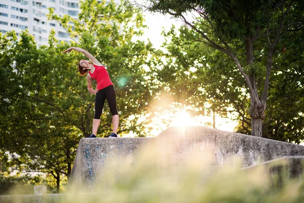Wanita muda melakukan olahraga di luar kota, peregangan . — Stok Foto