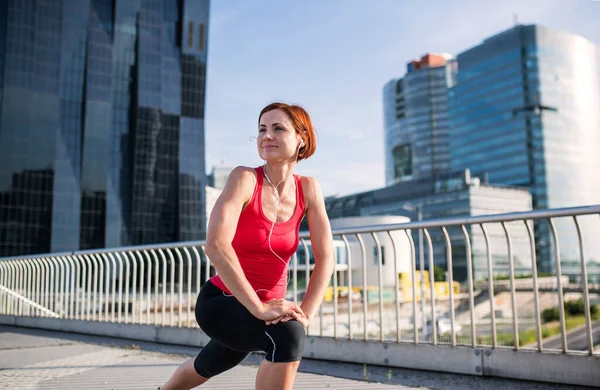 Giovane donna che fa esercizio fisico sul ponte all'aperto in città, stretching . — Foto Stock