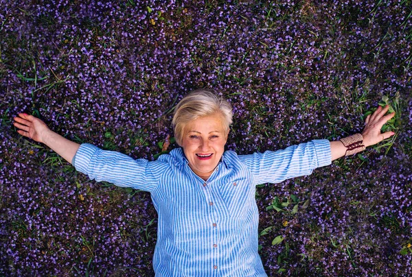 Seniorin auf Wiese liegend von oben gesehen. — Stockfoto